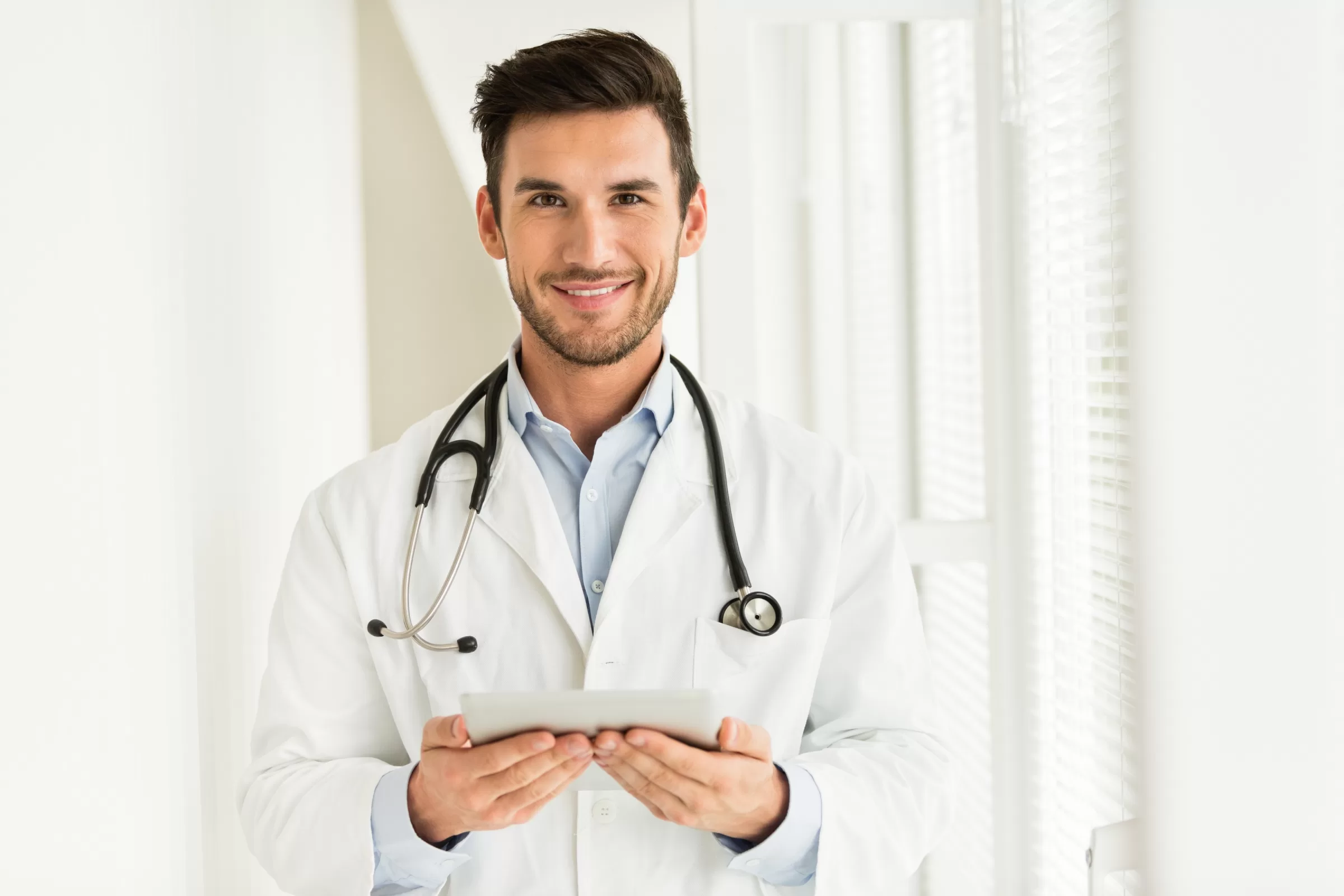 Doctor holding a tablet in a bright hospital corridor